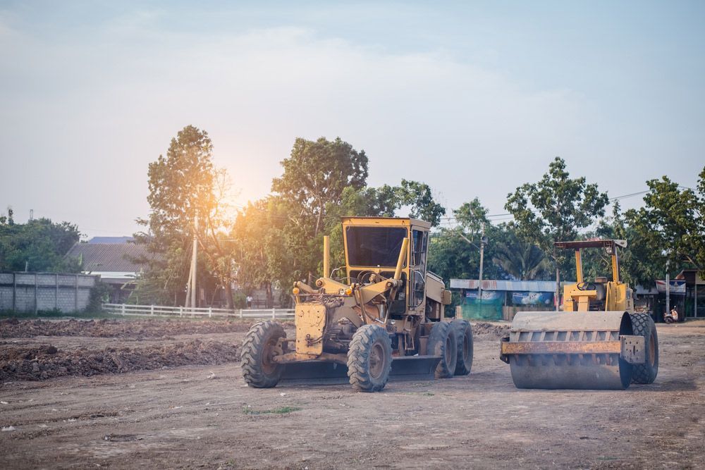 Yellow Construction Grader and Roller on a Dirt Construction Site — Huntlys Heavy Equipment in Gracemere, QLD