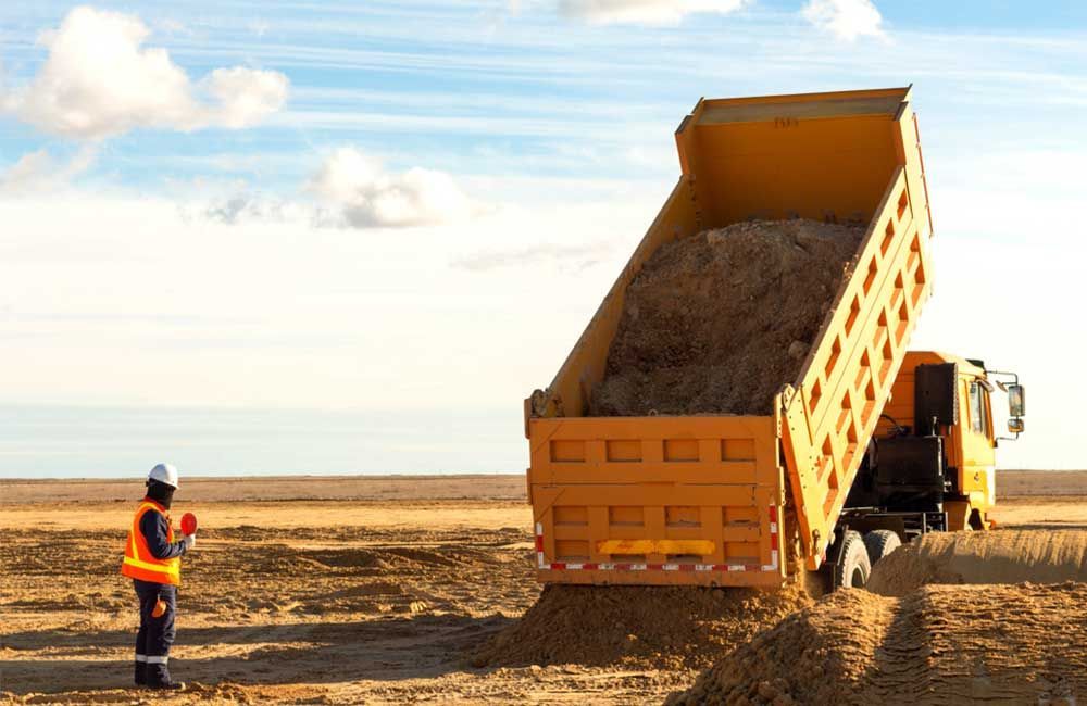 Yellow Dump Truck Unloading Gravel on a Construction Site — Huntlys Heavy Equipment in Gracemere, QLD