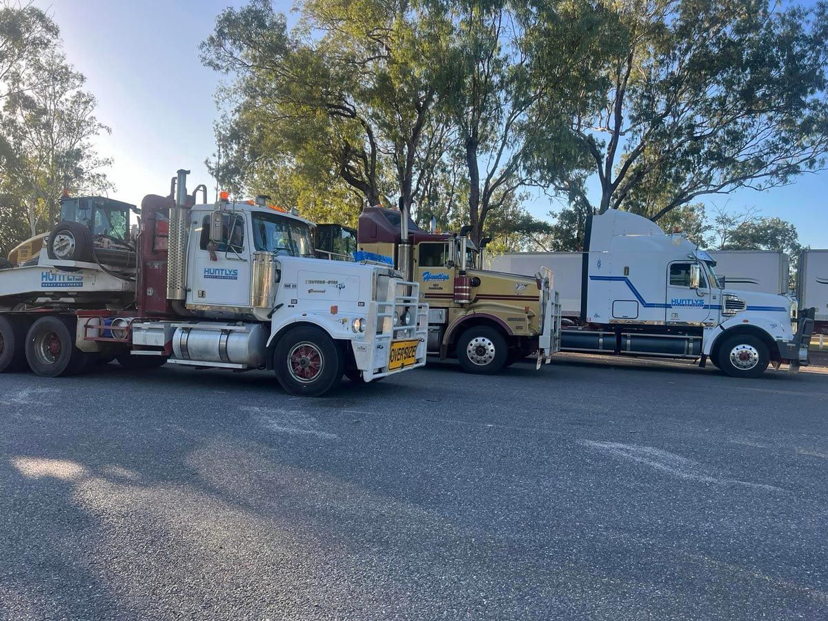 Several Weathered Semi-trucks Parked Outdoors on a Gravel Lot Under a Sunny Sky — Huntlys Heavy Equipment in Gracemere, QLD