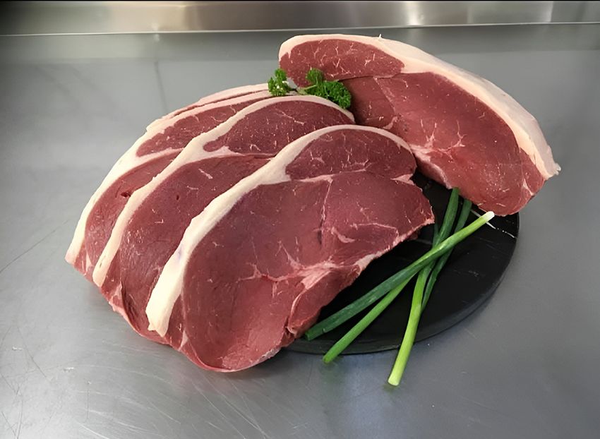 A Pile of Raw Steaks on a Black Plate with Green Onions — Midway Butchers in Tully, QLD