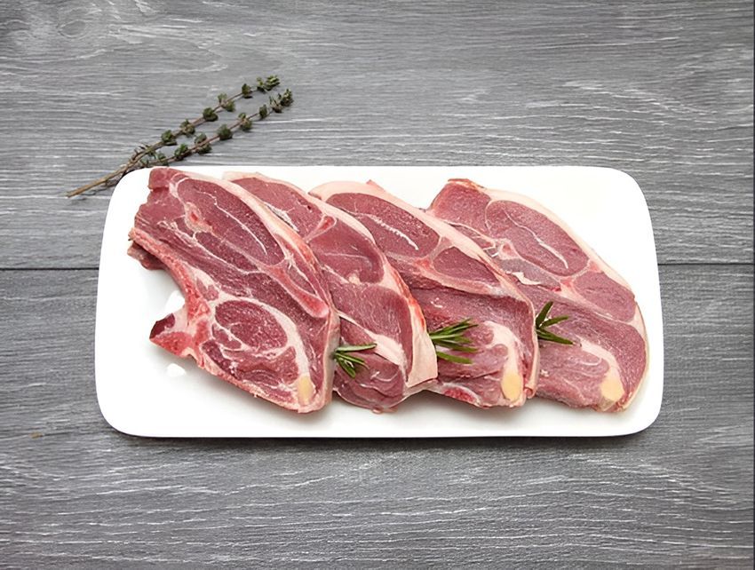 A White Plate Topped with Raw Lamb Chops on a Wooden Table — Midway Butchers in South Innisfail, QLD