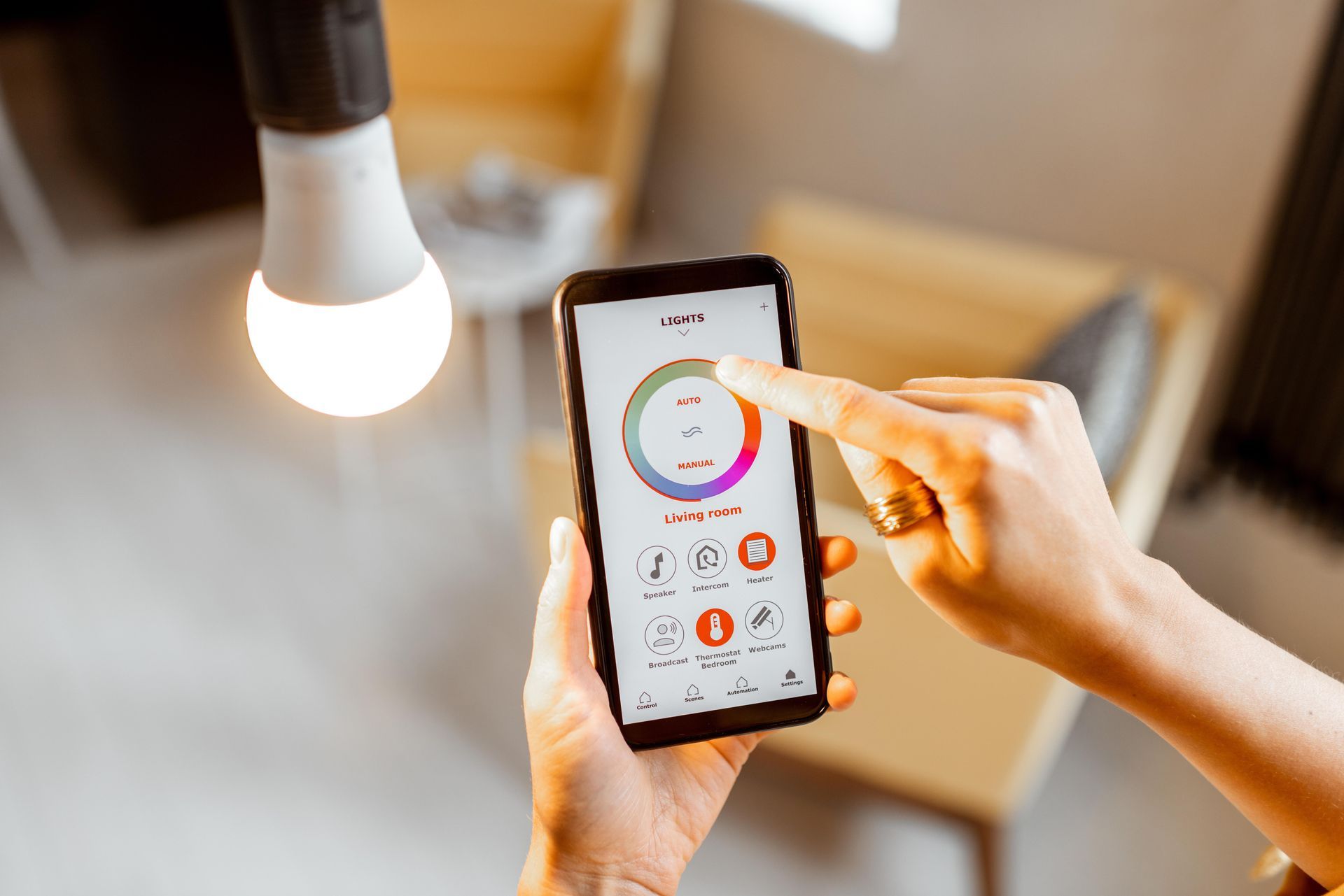 Person using a smartphone app to control a lit light bulb in a room