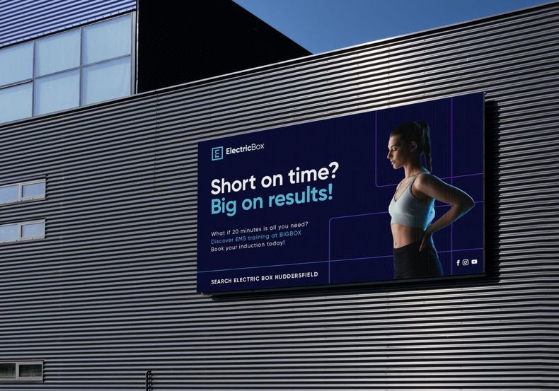 A billboard on the side of a building to advertise ElectricBox at BigBox Huddersfield that says 'short on time ? big on results ! ''