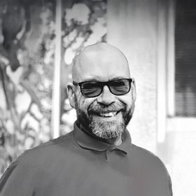 A man with a beard is smiling in a black and white photo.