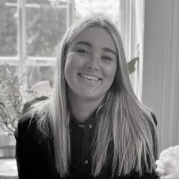 A woman in a striped shirt is smiling in a black and white photo.