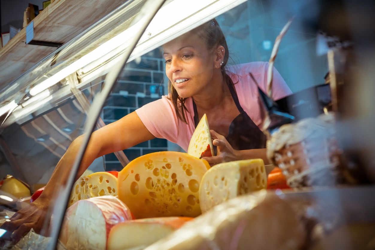 Vendor serving flatbreads at a market stall, with colorful food displayed in the foreground.