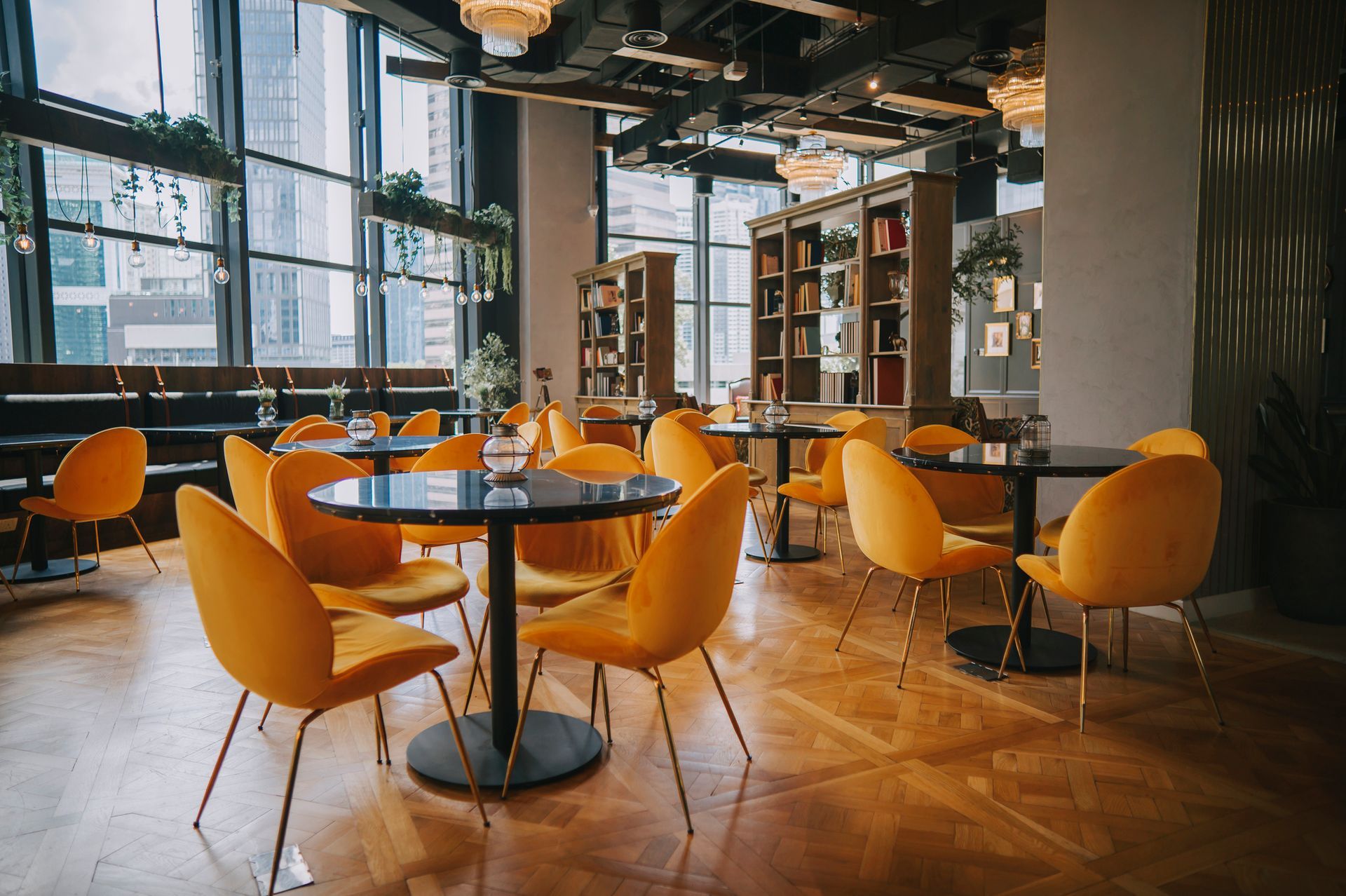 Modern café interior with yellow chairs, round tables, and large windows by a wooden floor