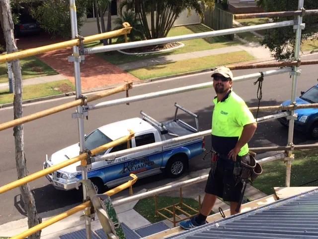 A Man is Standing on Top of a Roof Next to a Truck — Roofing Revamped in Maroochydore, QLD