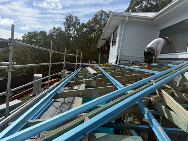 A Man Is Working On The Roof Of A House — Roofing Revamped in Maroochydore, QLD