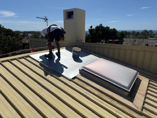 A Man With A Bucket Is Working On The Roof Of A House — Roofing Revamped in Maroochydore, QLD