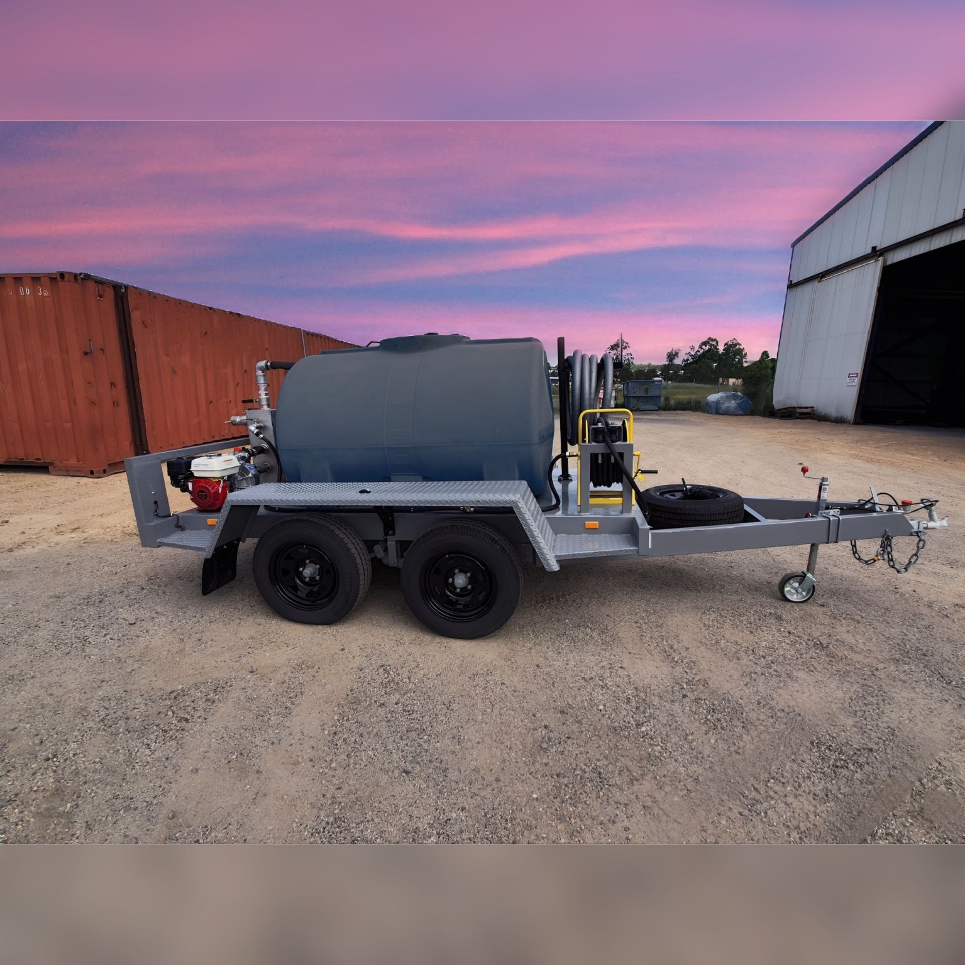 A trailer with a large tank on it is parked in front of a building.