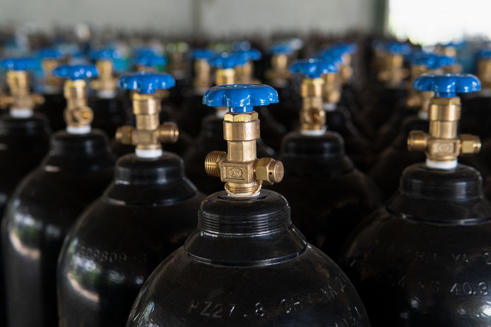 A Row of Black Gas Cylinders with Blue Valves in A Warehouse — Eddies Trailers & Fab in Muswellbrook, NSW