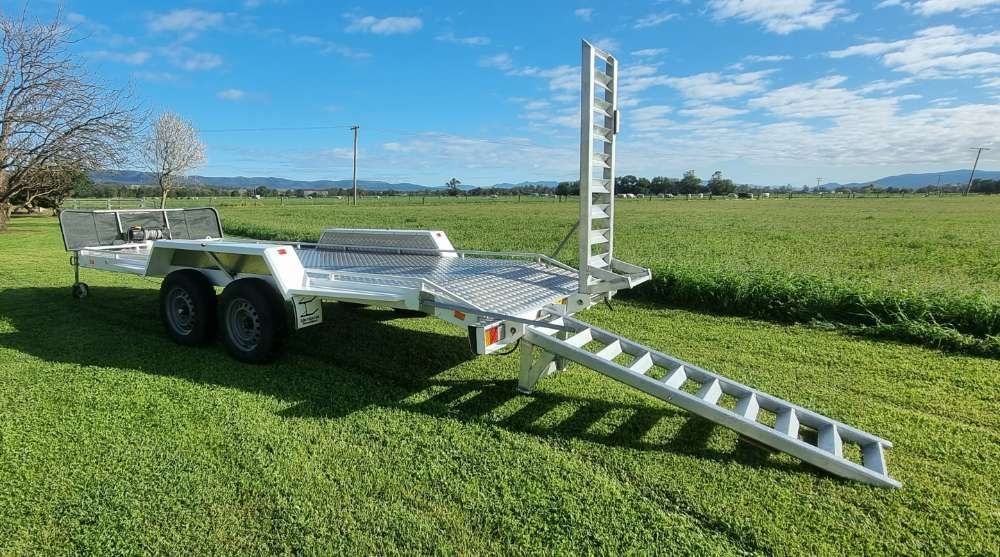 A Trailer With A Ramp Attached To It Is Parked In A Grassy Field — Eddies Trailers & Fab in Muswellbrook, NSW
