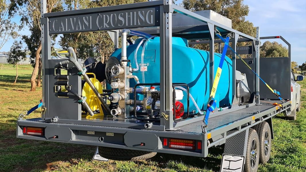 A Trailer with A Machine on It Is Parked in A Grassy Field — Eddies Trailers & Fab in Muswellbrook, NSW