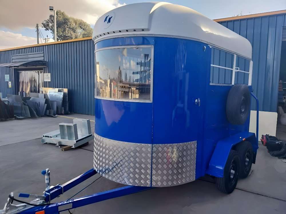 A Blue And White Trailer Is Parked In Front Of A Building — Eddies Trailers & Fab in Muswellbrook, NSW