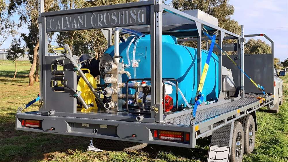A Trailer With A Machine On It Is Parked In A Grassy Field — Eddies Trailers & Fab in Muswellbrook, NSW
