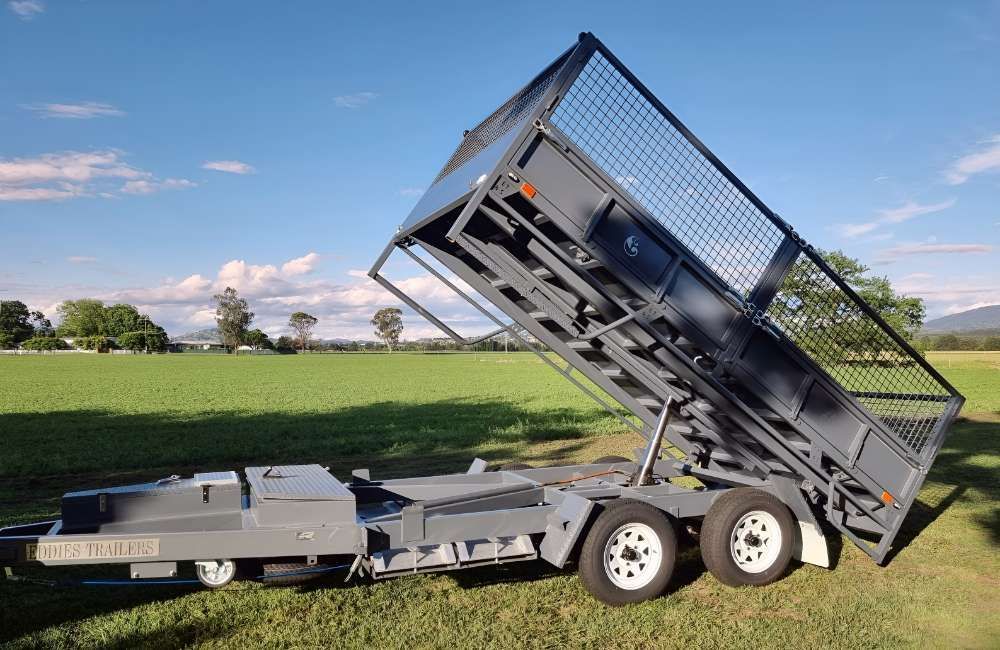 A Dump Trailer Is Parked In A Grassy Field — Eddies Trailers & Fab in Muswellbrook, NSW