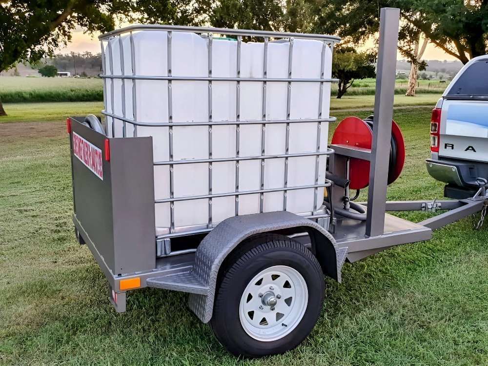 A Trailer With A Large White Tank On It Is Parked In A Grassy Field — Eddies Trailers & Fab in Muswellbrook, NSW