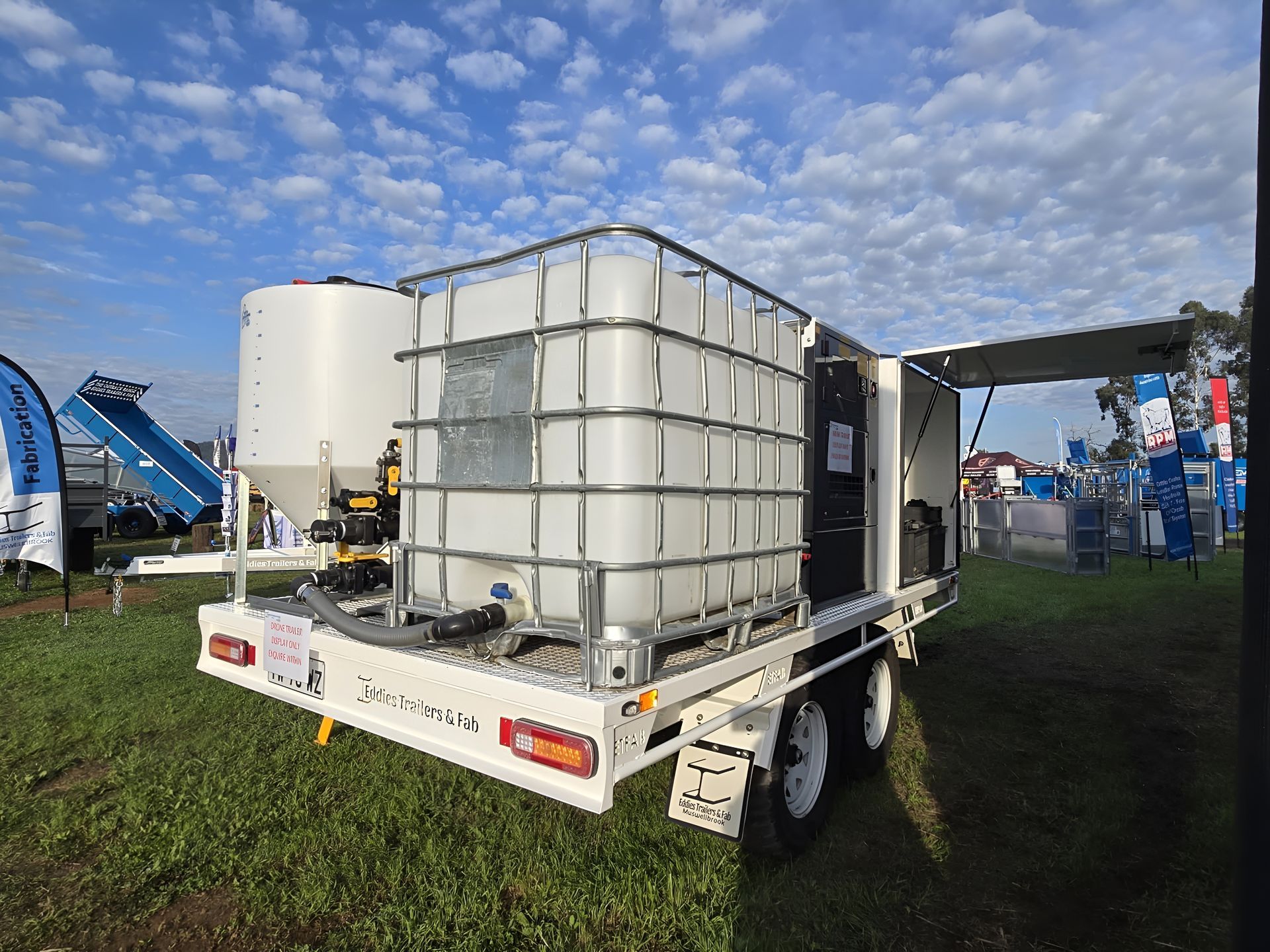 A trailer with a lot of containers on it is parked in a grassy field.