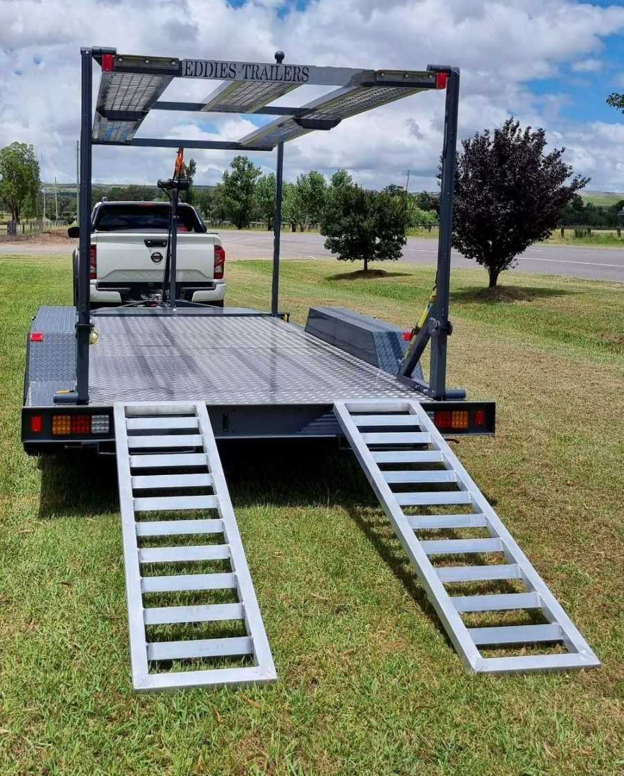 A Trailer With Ramps Attached To It Is Parked In A Grassy Field — Eddies Trailers & Fab in Muswellbrook, NSW