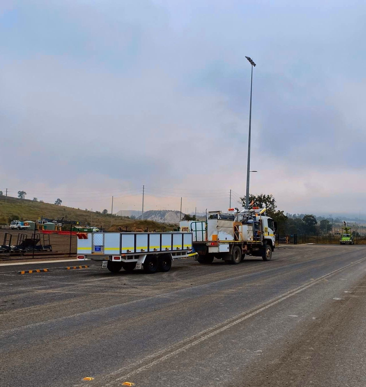 A truck with a trailer attached to it is parked on the side of the road