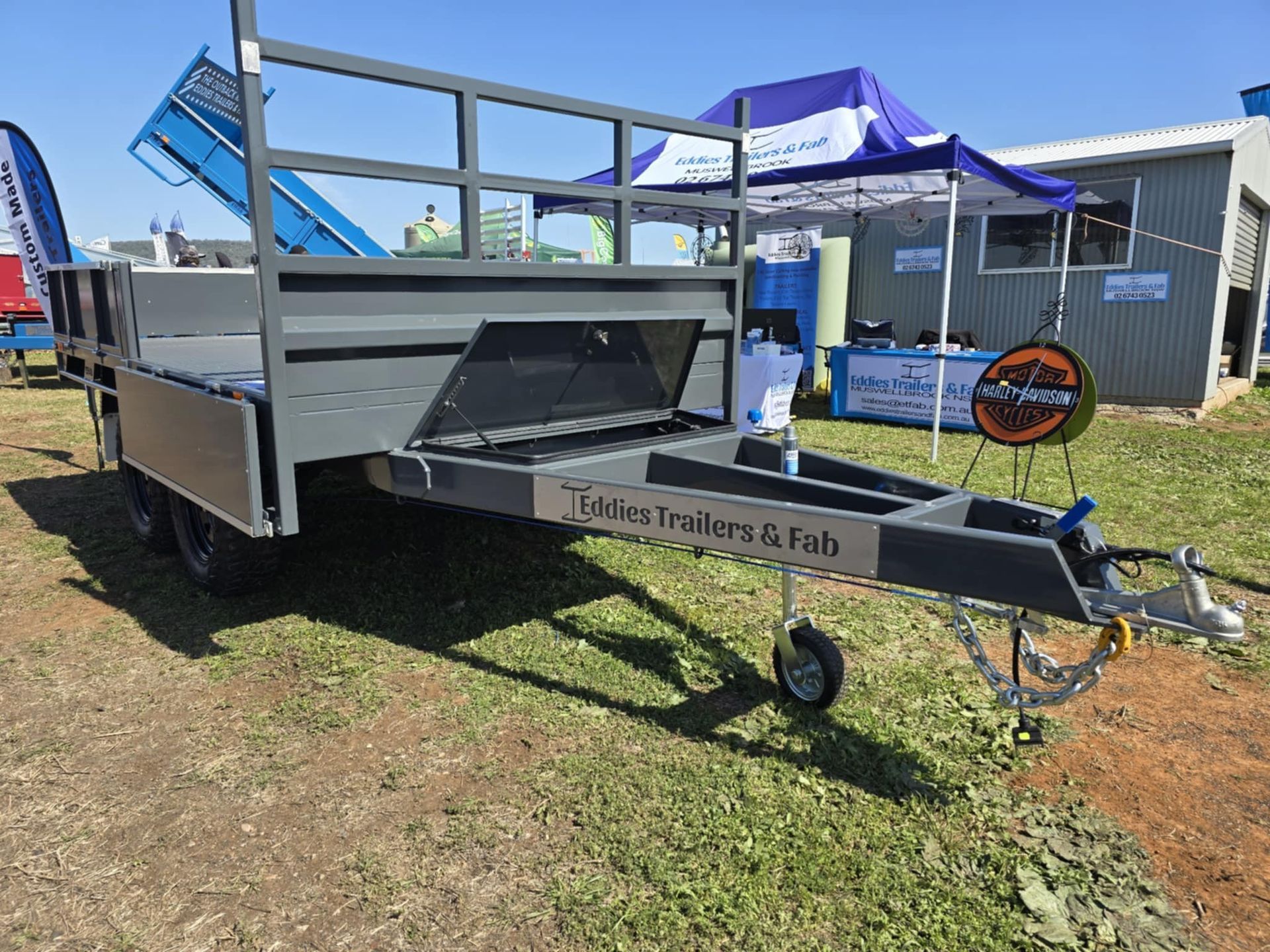 A trailer is parked in the grass in front of a building.