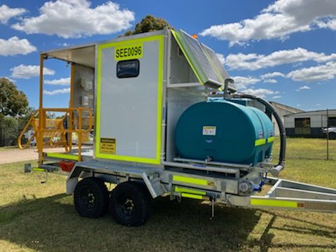 A Trailer With Two Tanks Attached To It Is Parked In A Grassy Field — Eddies Trailers & Fab in Muswellbrook, NSW