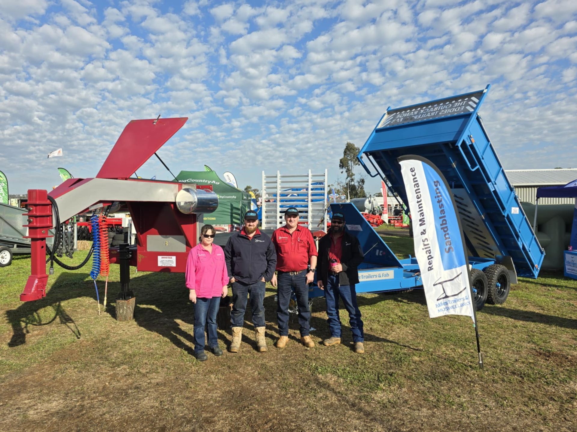 A group of people are posing for a picture in front of a dump truck.