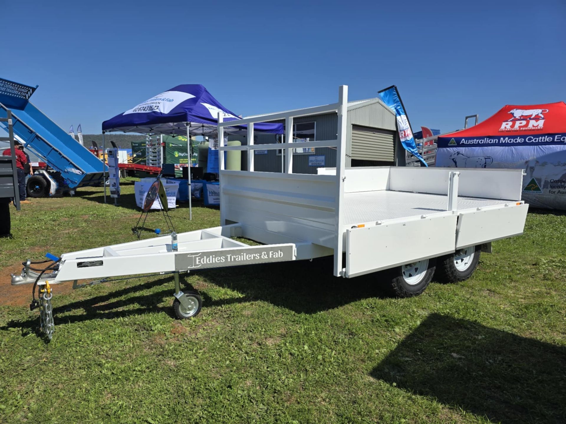 A white trailer is parked in a grassy field.