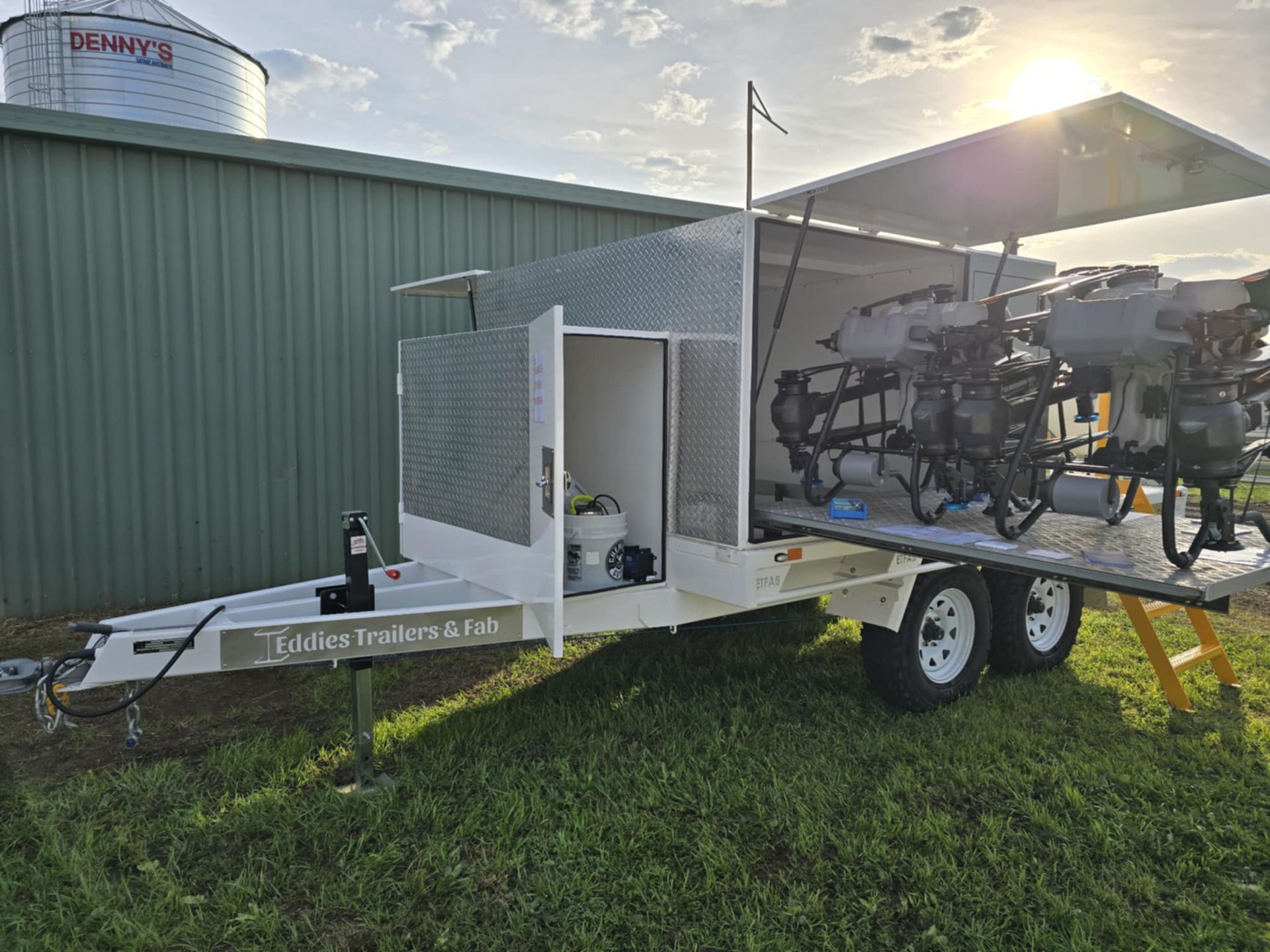 A trailer is parked in a grassy field next to a building.