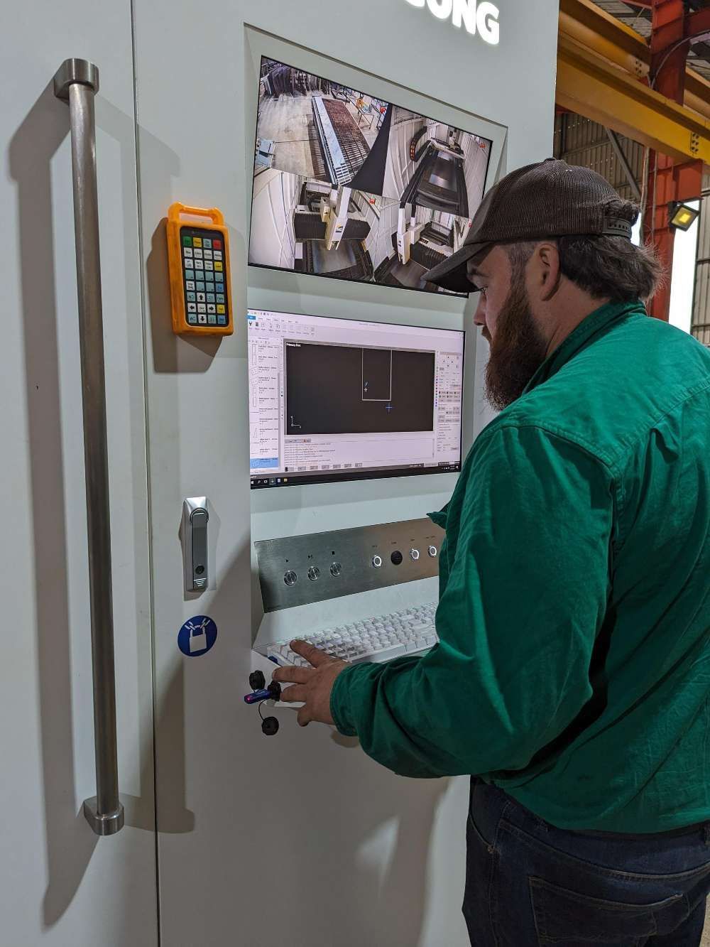 A Man In A Green Jacket Is Working On A Machine — Eddies Trailers & Fab in Muswellbrook, NSW