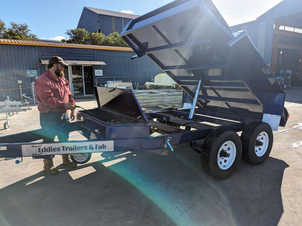 A Man Is Standing Next To A Dump Trailer With The Lid Open — Eddies Trailers & Fab in Muswellbrook, NSW