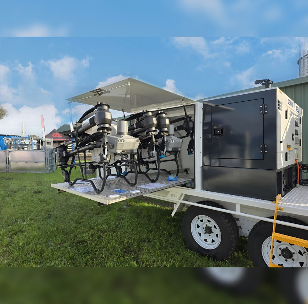 A trailer with a lot of machinery on it is parked in the grass.