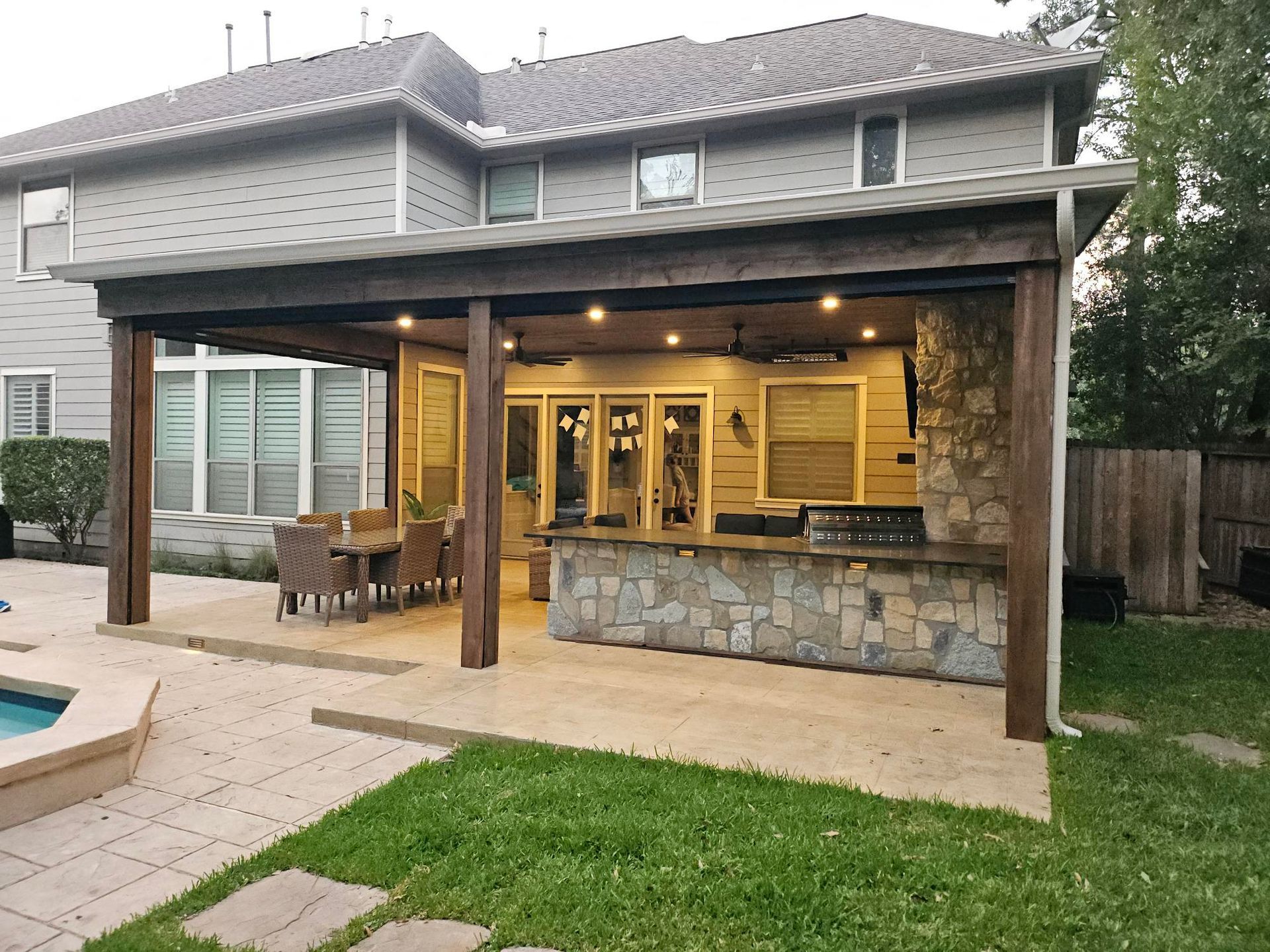 Outdoor patio with kitchen, dining set, and stone accents.
