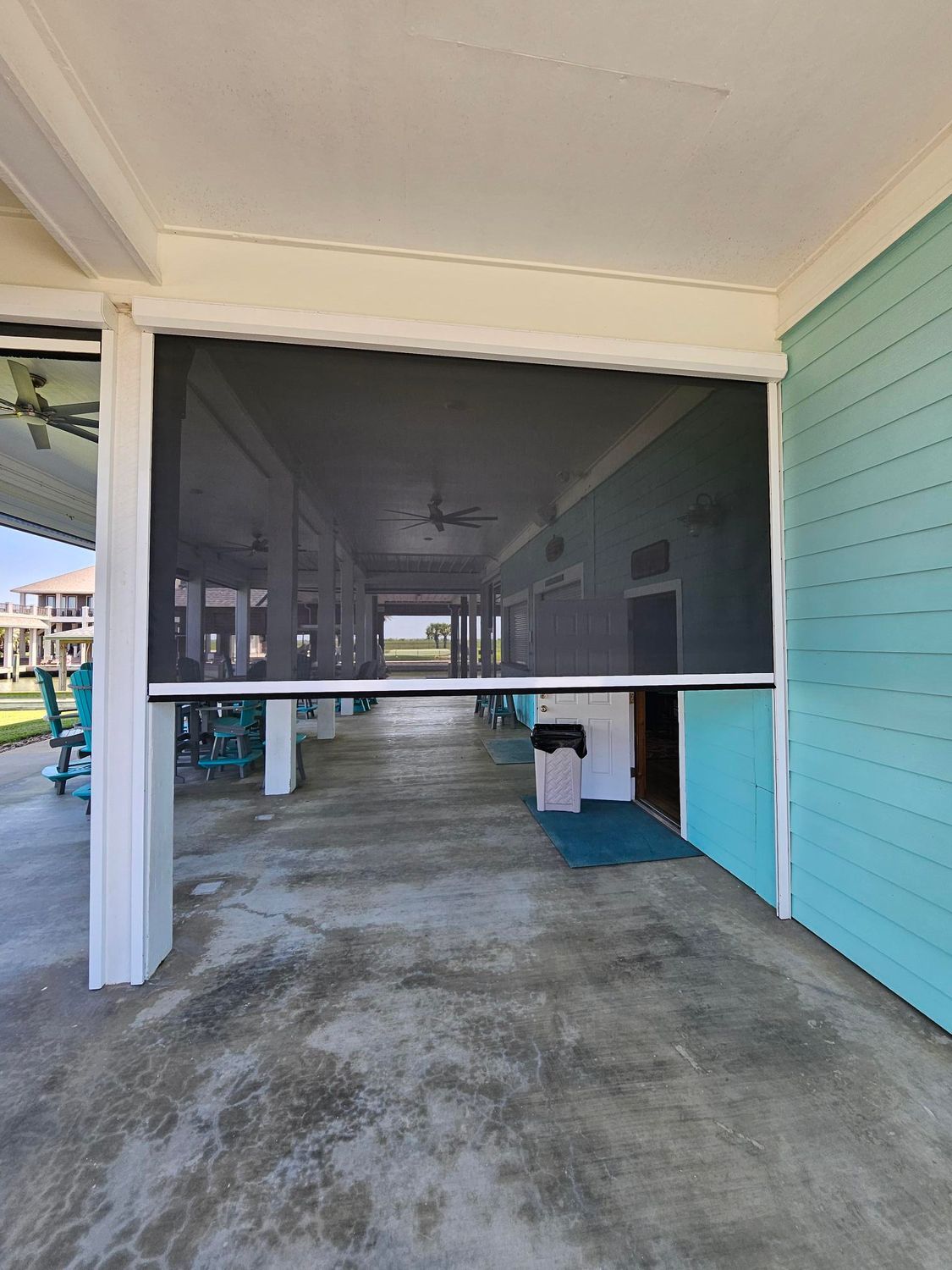 Exterior view of a screened porch; a partially lowered, black screen blocks the opening.
