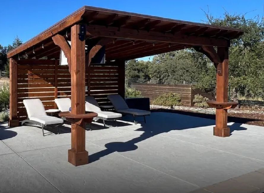 Wooden pergola over lounge chairs on a concrete patio.