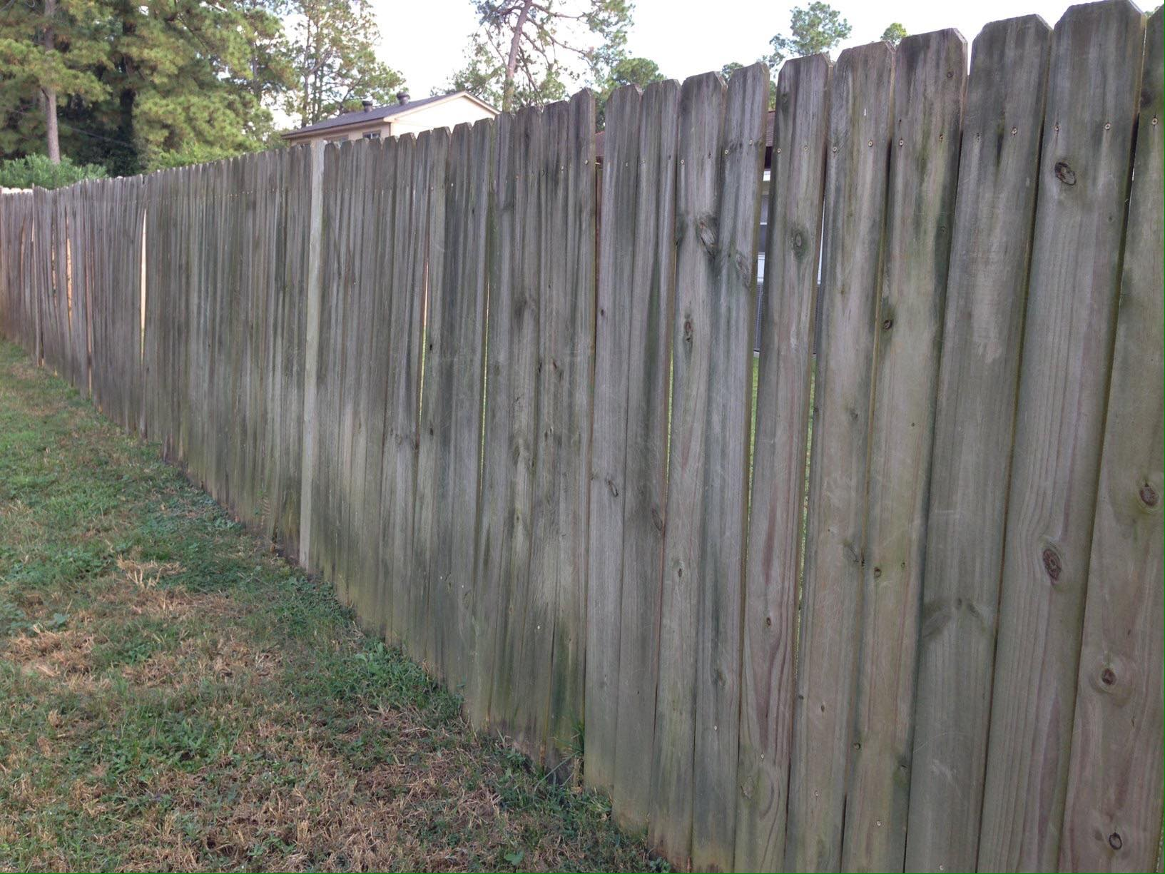 Weathered wooden fence with green grass in front.