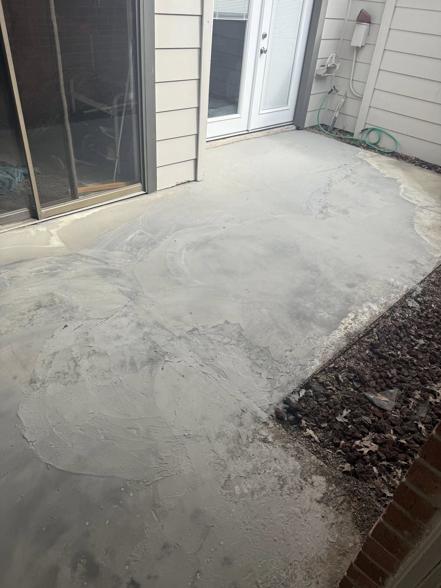 Grey concrete patio with white door and sliding glass door.