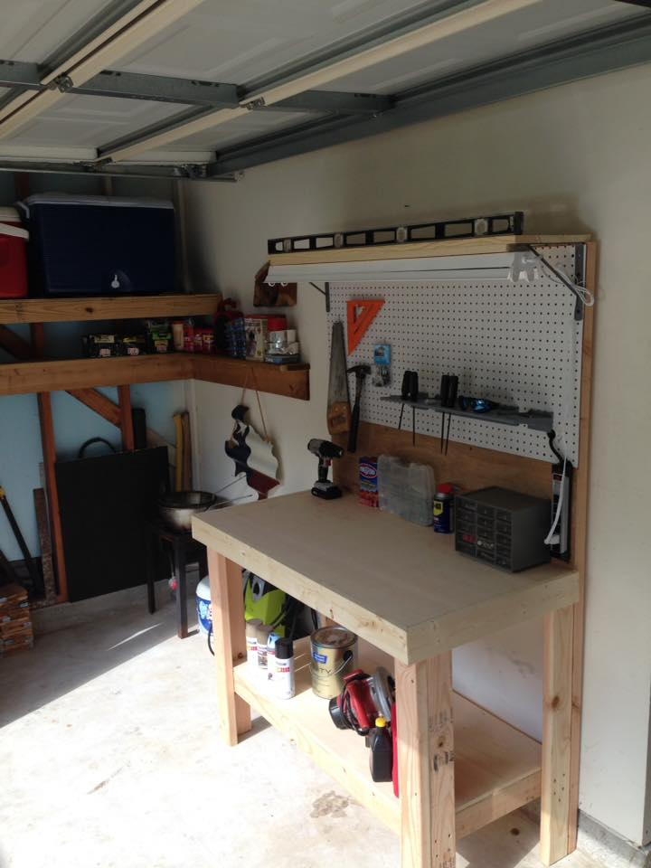 Workshop with workbench, pegboard, tools, and shelves. Light wood, concrete floor, garage setting.