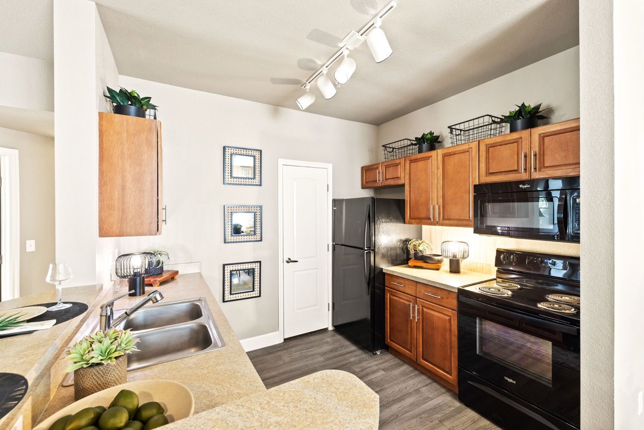 Kitchen in an apartment with wooden cabinets, a double sink, and black appliances.