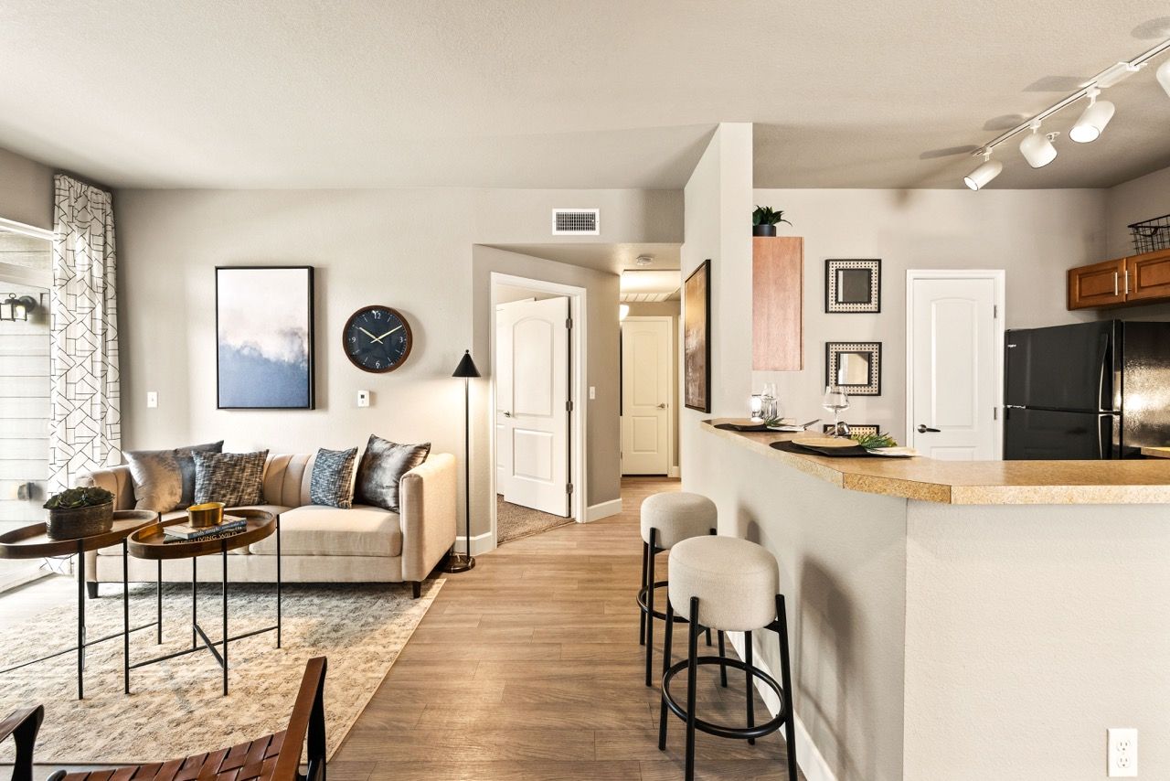 Open-concept living room with a beige sofa, round coffee tables, and a breakfast-bar counter.