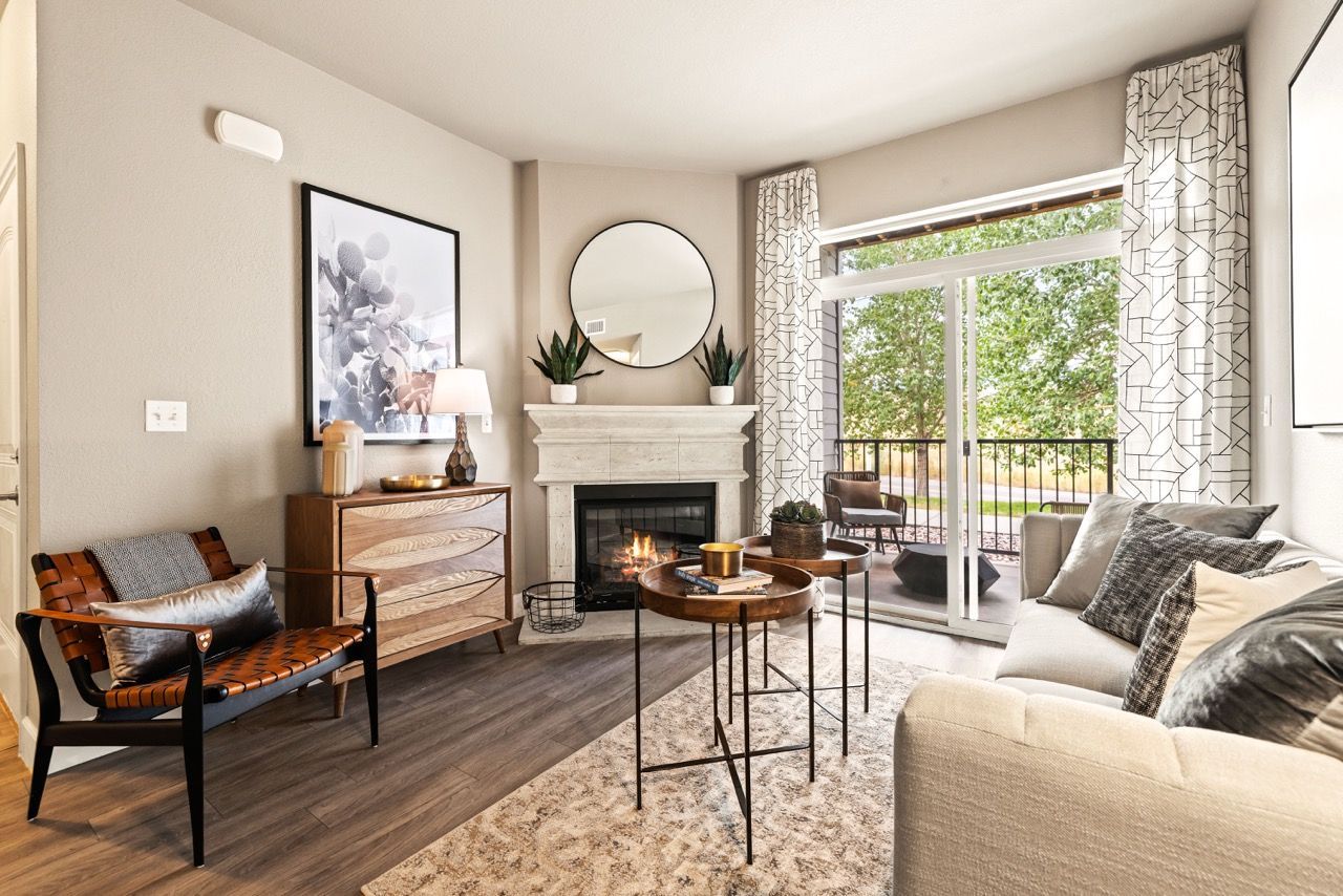 Apartment living room with a fireplace, sofa, chairs, and sliding balcony door.