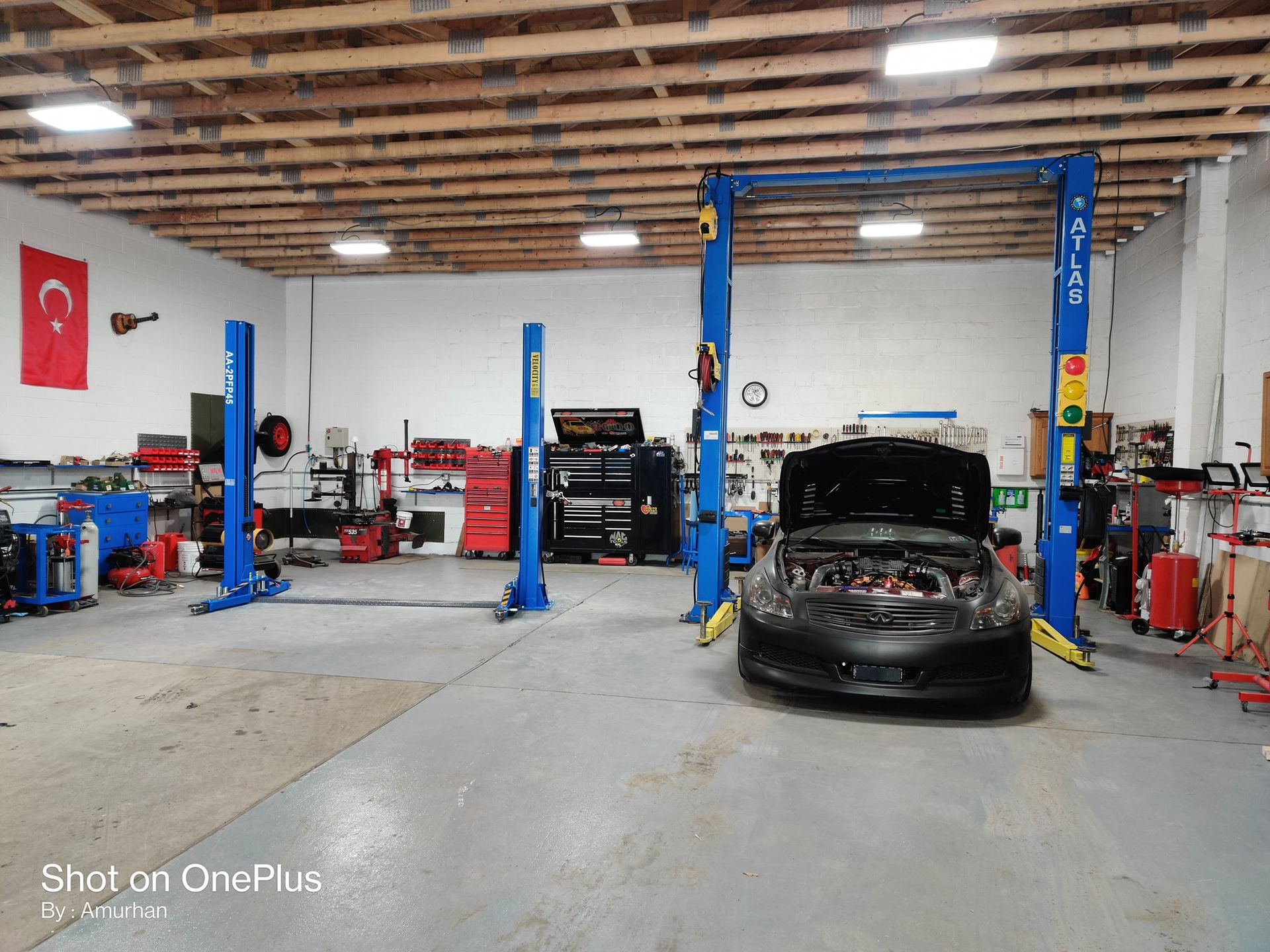 An auto repair shop with three blue car lifts. A car is parked on one lift.
