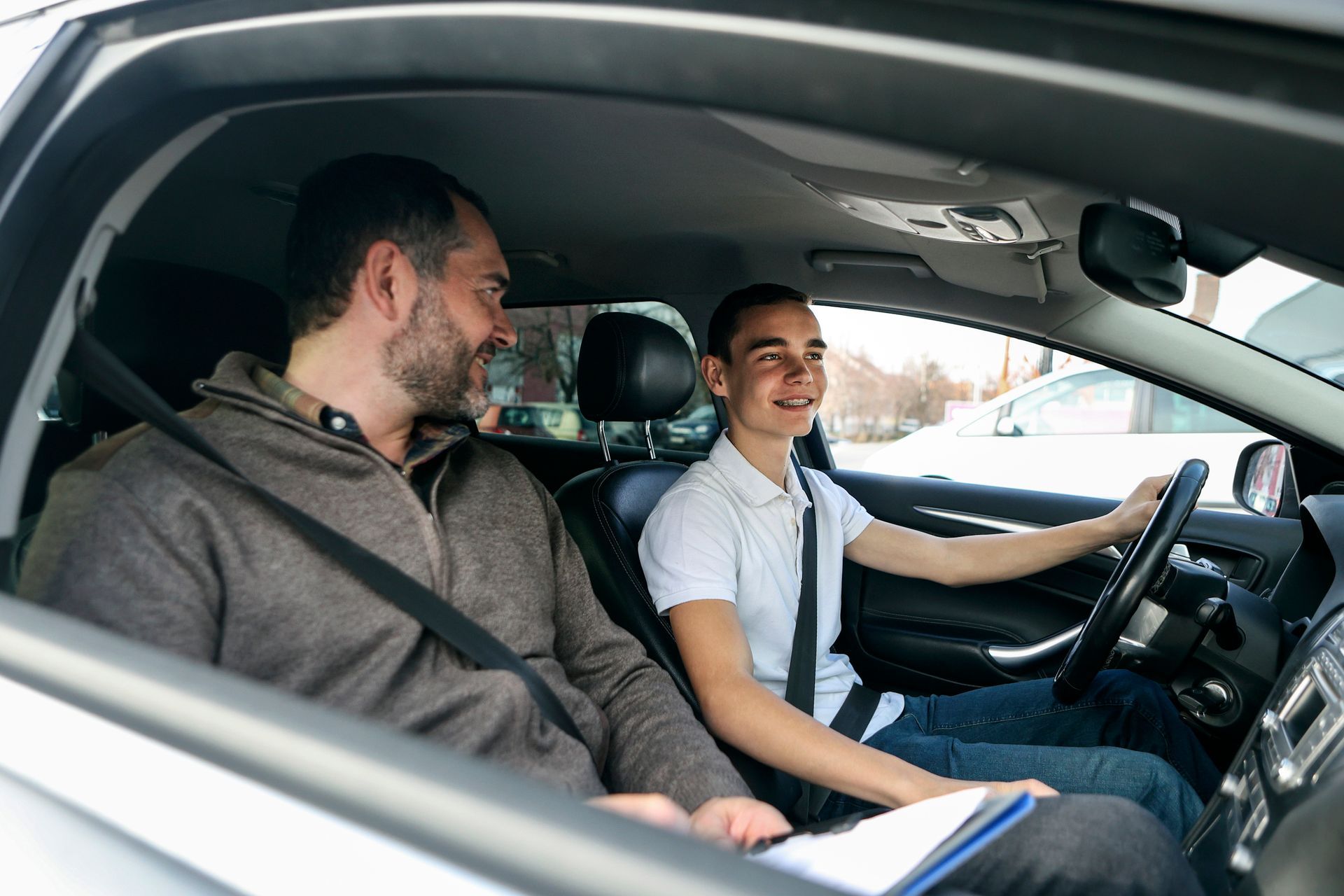 Male teenager learning how to drive a car with male driving instructor.