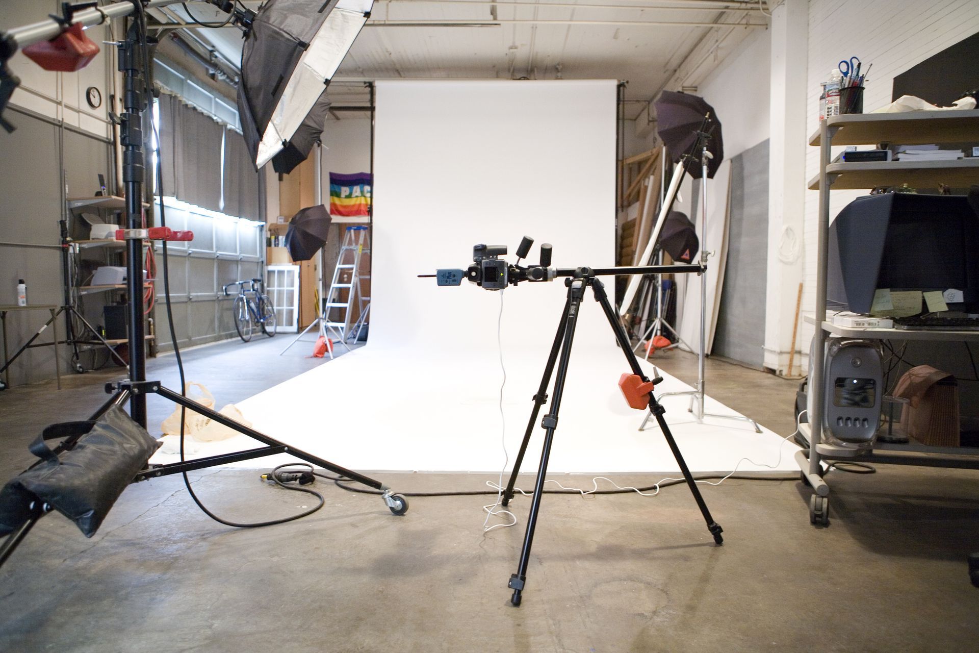A photo studio with a white backdrop and a camera on a tripod