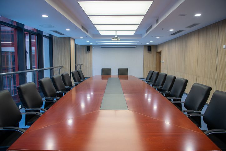 An empty conference room with a long table and chairs.