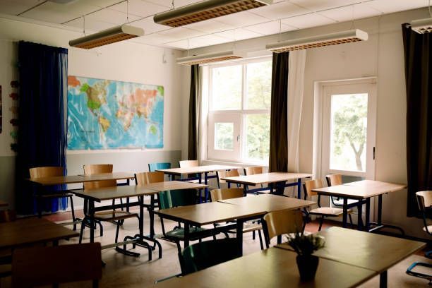 A classroom with tables and chairs and a map on the wall.
