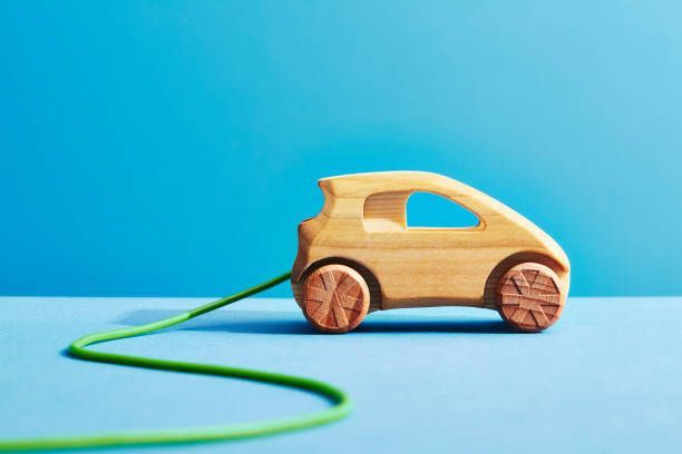 A wooden toy car is plugged into a green cord.