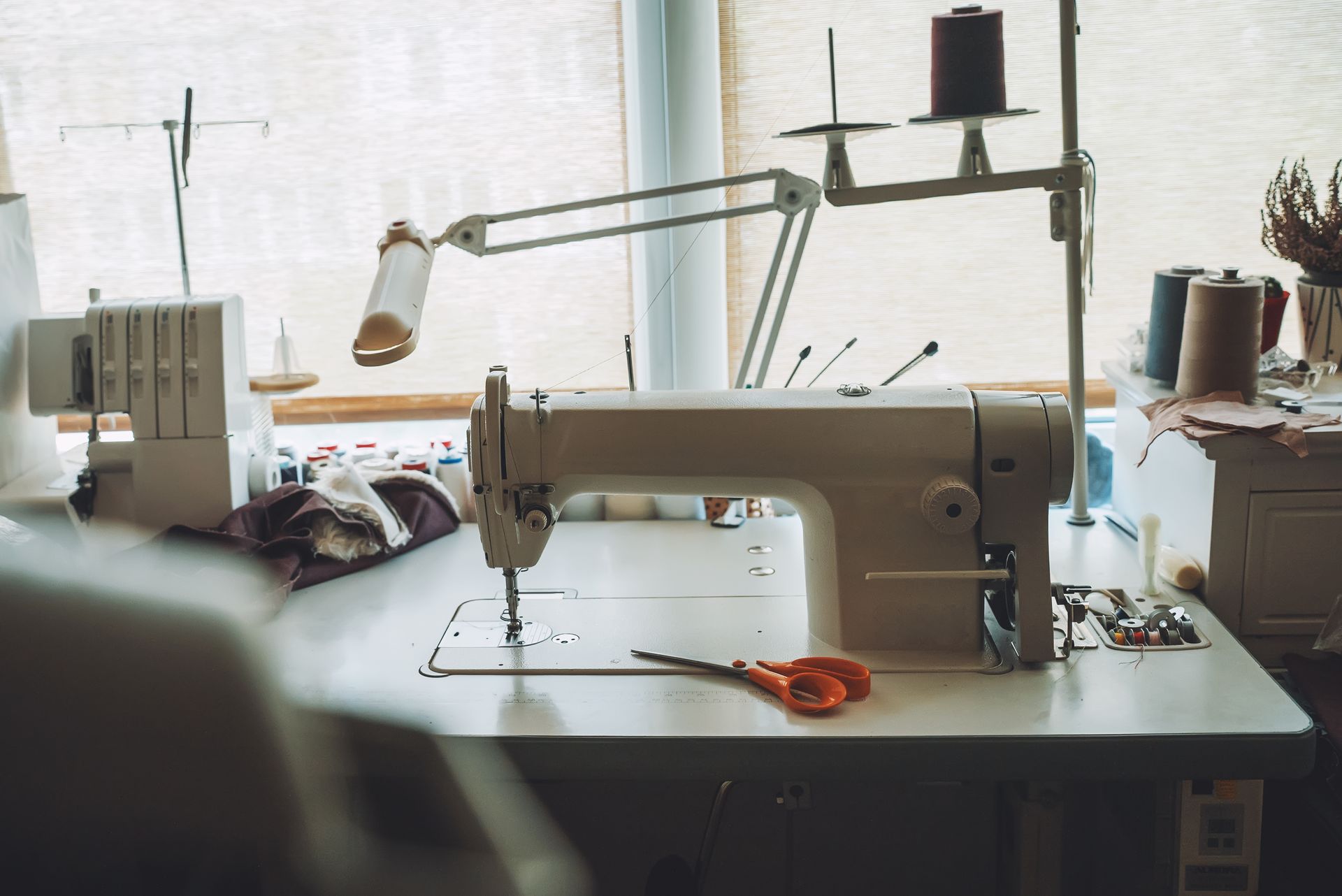 A sewing machine is sitting on a table next to a window.