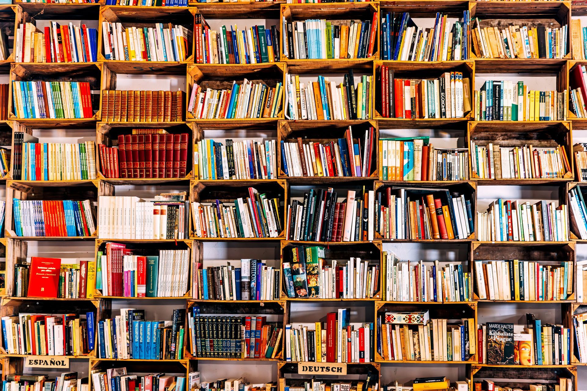 A library filled with lots of books on wooden shelves.